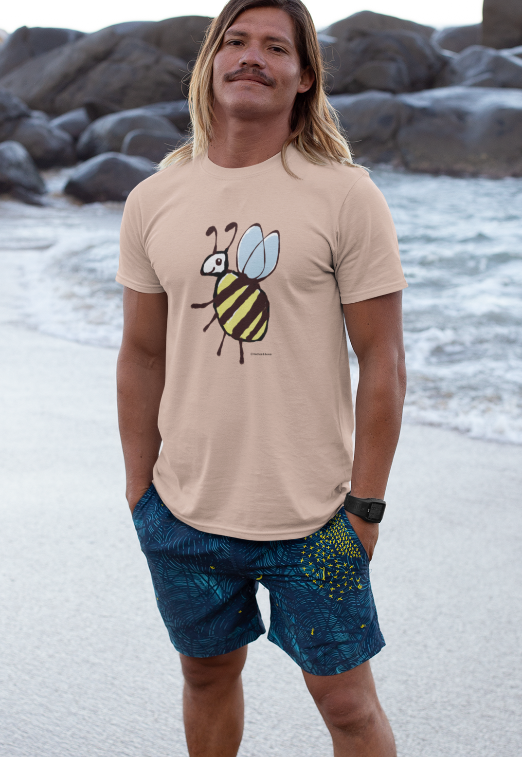 Bee T-shirt - Young man on beach wearing a cute Busy Bee illustrated Fresh Peche colour vegan cotton t-shirts by Hector and Bone