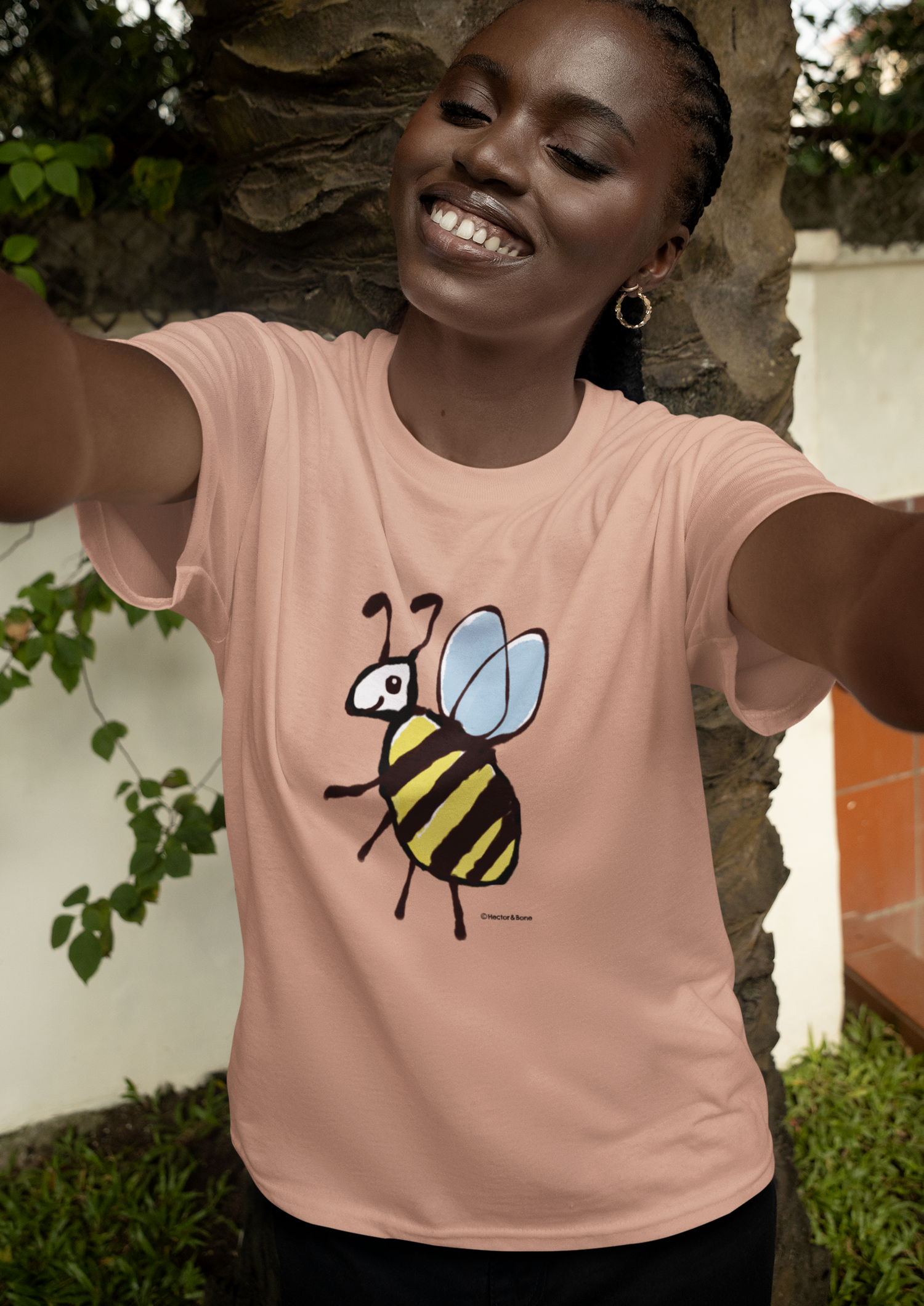 Bee T-shirt - Young woman in garden wearing a cute Busy Bee illustrated vegan cotton t-shirts by Hector and Bone