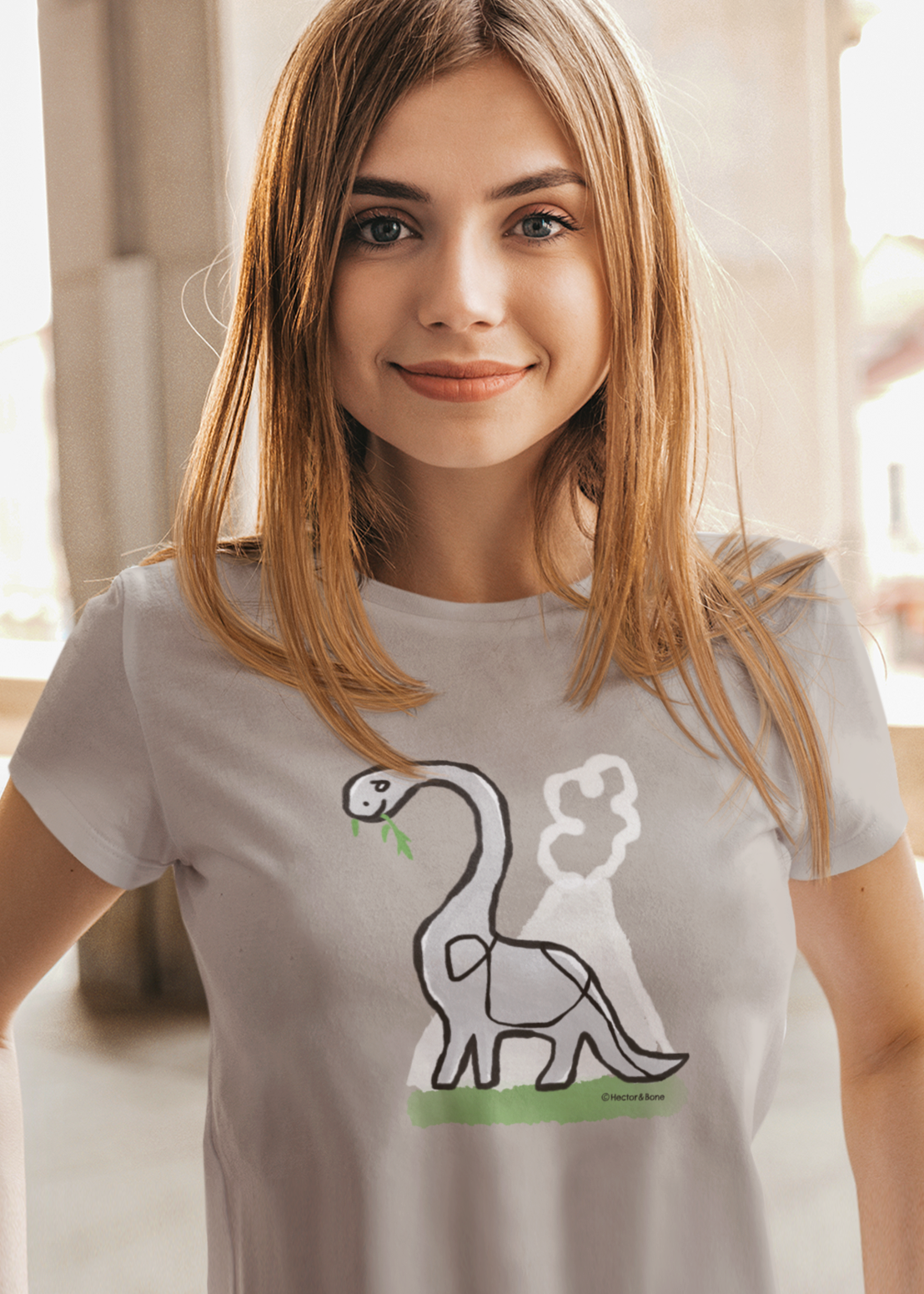 Young girl wearing a Dinosaur T-shirt illustrated on a Desert Dust colour Brontosaurus Tshirt design by Hector and Bone