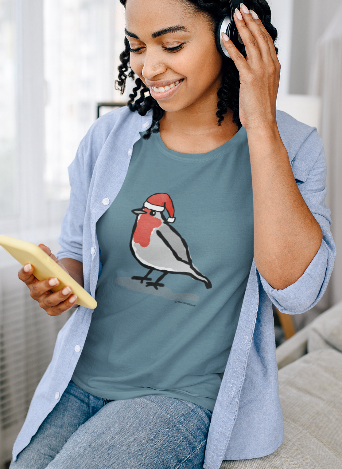 Young woman relaxing at Xmas, wearing a illustrated Santa Christmas Robin T-shirt - Stargazer Blue colour vegan cotton Christmas T-shirts by Hector and Bone