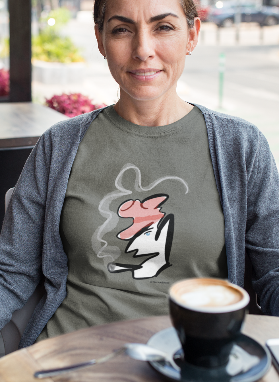 Woman wearing a stylised illustrated design of Parisian smoking man portrait on a khaki colour vegan cotton t-shirt by Hector and Bone