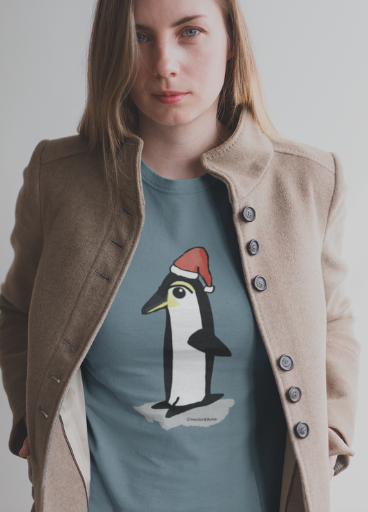 Christmas Penguin T-shirt - Young woman wearing a Santa Penguin cute Christmas T-shirt in stargazer blue colour illustrated design by Hector and Bone on a Vegan cotton t-shirt