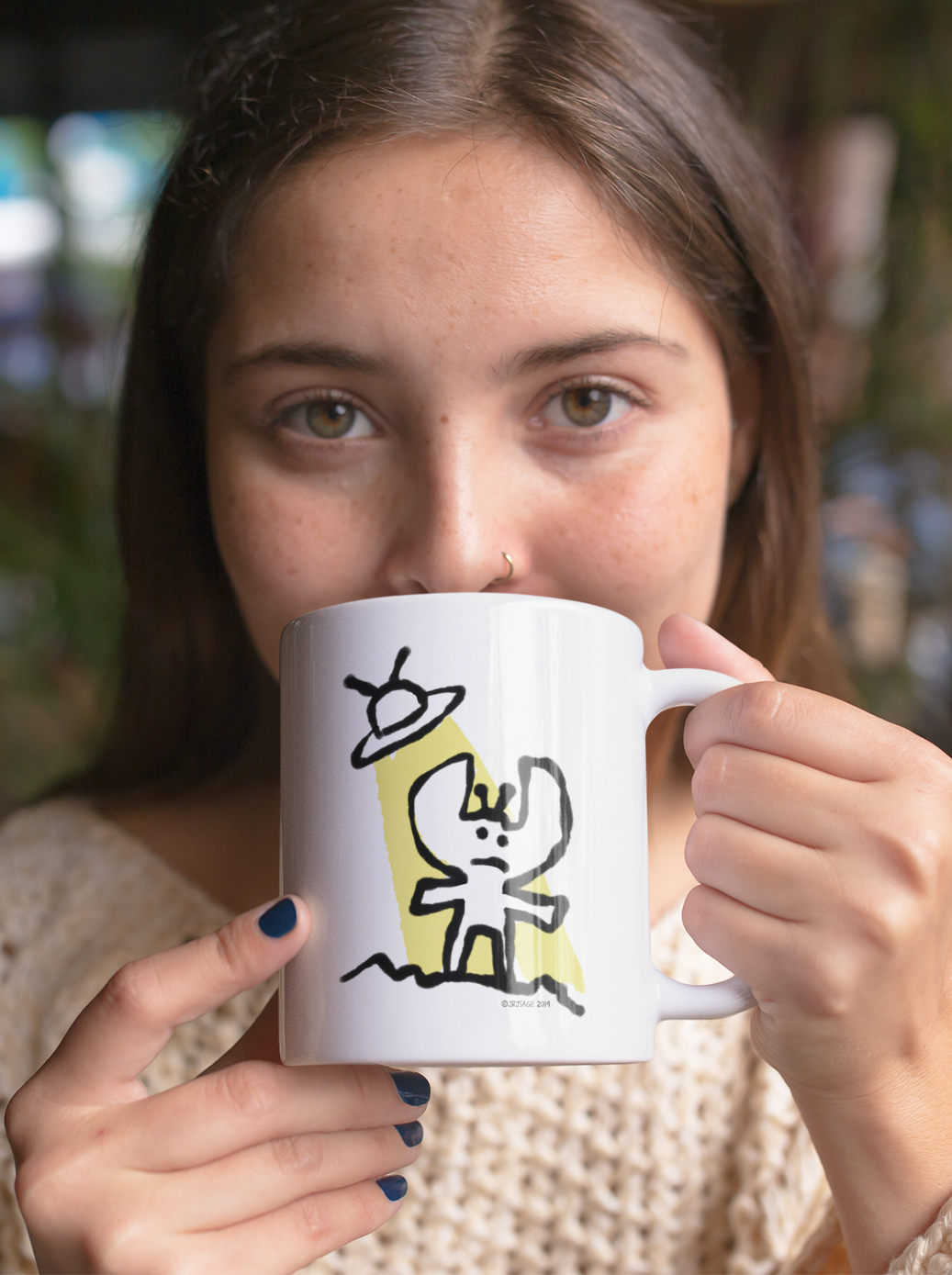 A young girl drinking from a White Ceramic Hector and Bone Mug with an illustration of an Alien and his Spaceship