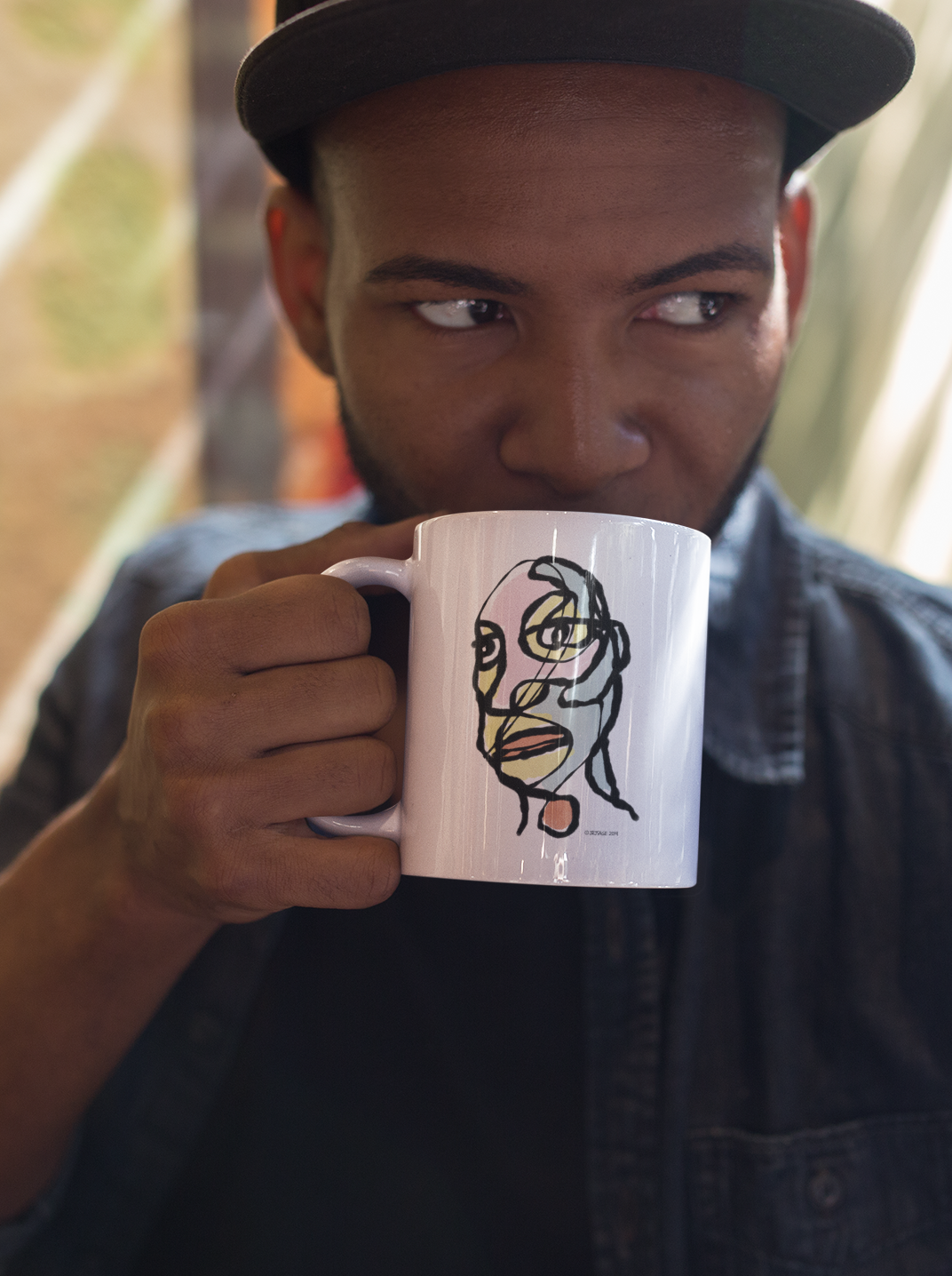 A man drinking from a White Ceramic Hector and Bone Mug with a quirky illustration of an arty abstract portrait