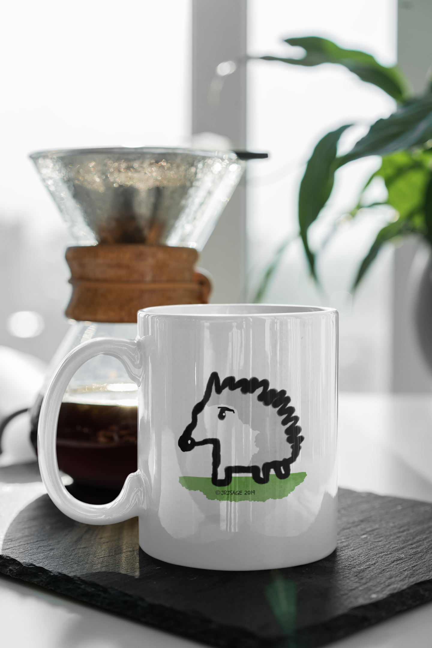 A White Ceramic Hector and Bone Mug with an illustration of a cute Baby Hedgehog on a table