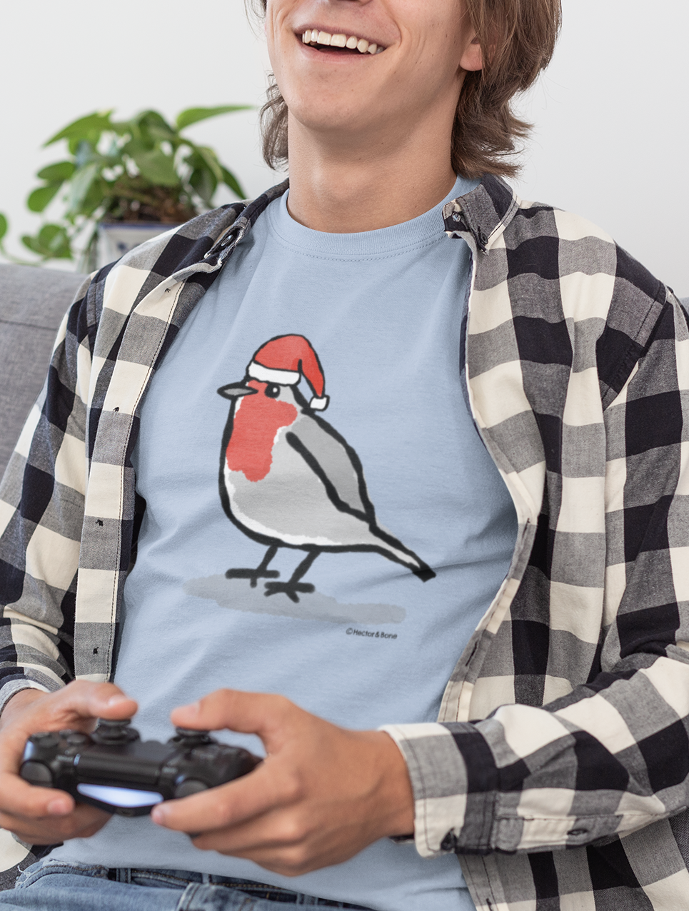 Young man relaxing at Xmas, wearing a illustrated Santa Christmas Robin T-shirt - Sky Blue colour vegan cotton Christmas T-shirts by Hector and Bone 