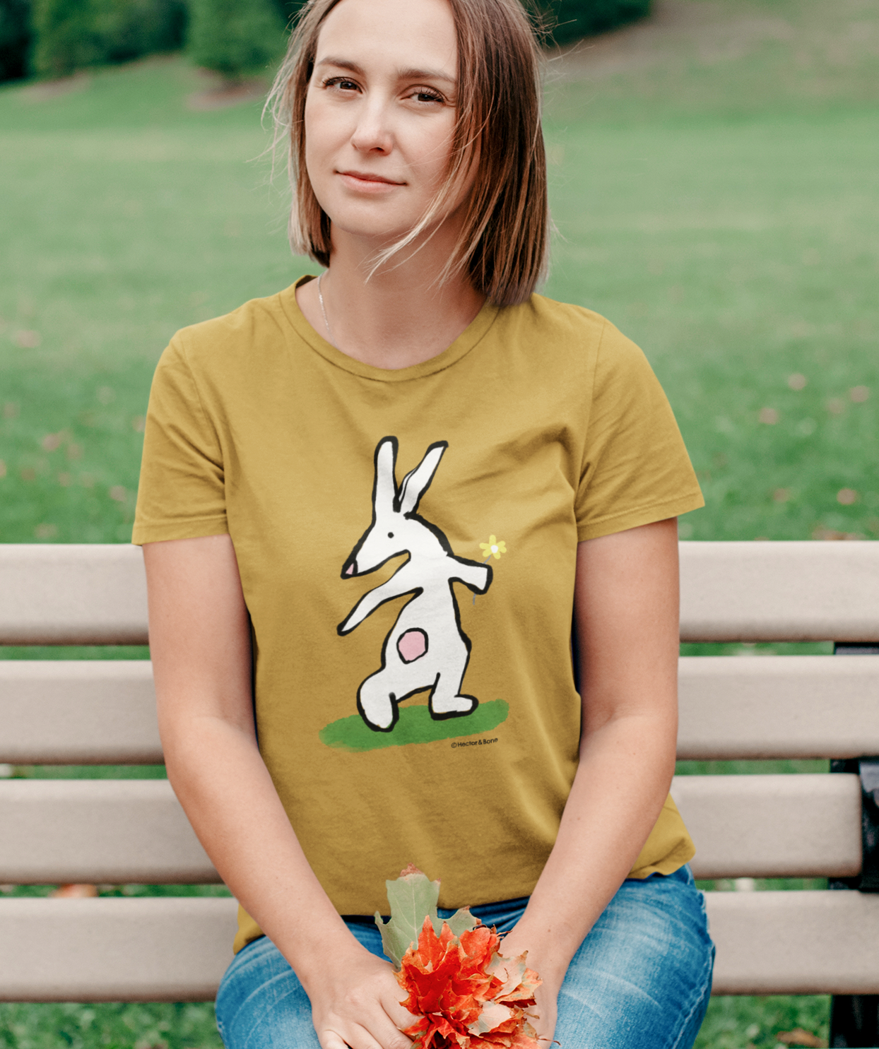 Bunny T-shirt - Young woman wearing Illustrated bunny rabbit holding a flower design on a ochre colour vegan cotton t-shirt - Easter Bunny t-shirts by Hector and Bone