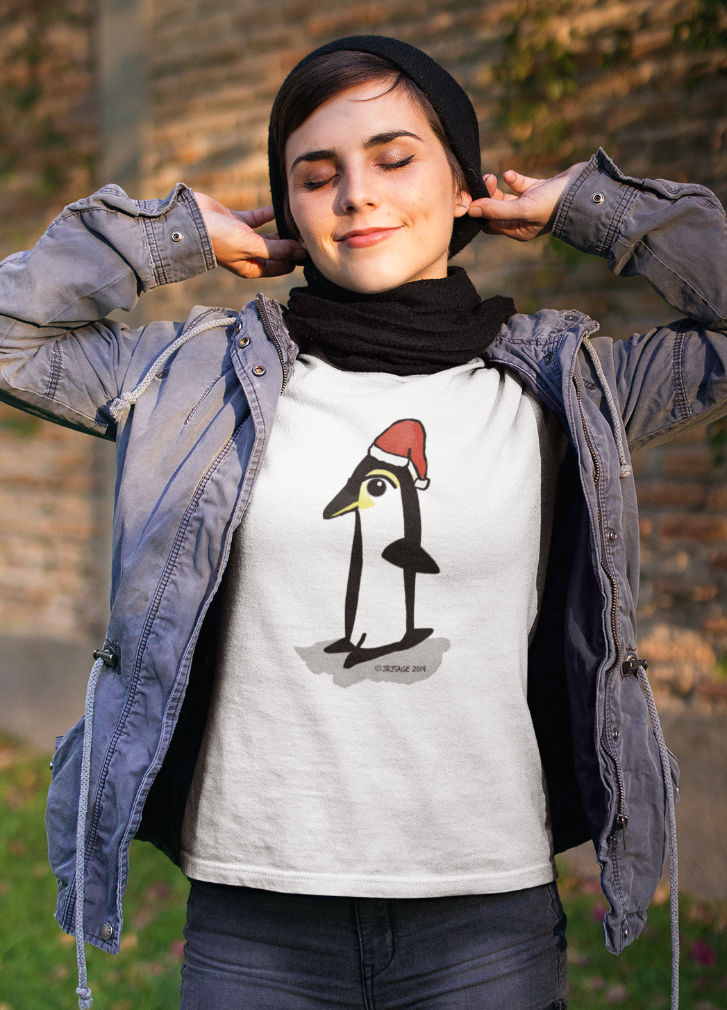 Young woman outside wearing a Santa Penguin cute Christmas T-shirt illustrated design by Hector and Bone on a white vegan cotton t-shirt