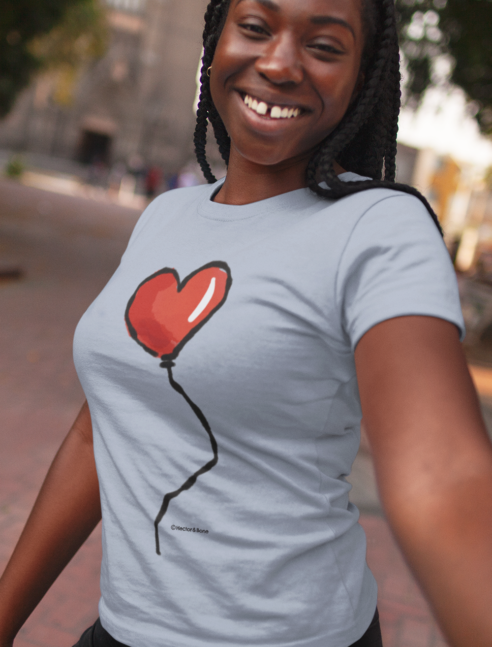 Smiling woman wearing a Red Heart Balloon I Love you T-shirt design printed on a sky blue colour vegan cotton t-shirt by Hector and Bone
