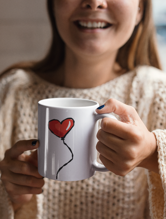 Red Heart Balloon I Love you illustration by Hector and Bone printed on a quality ceramic coffee mug held by a smiling young woman